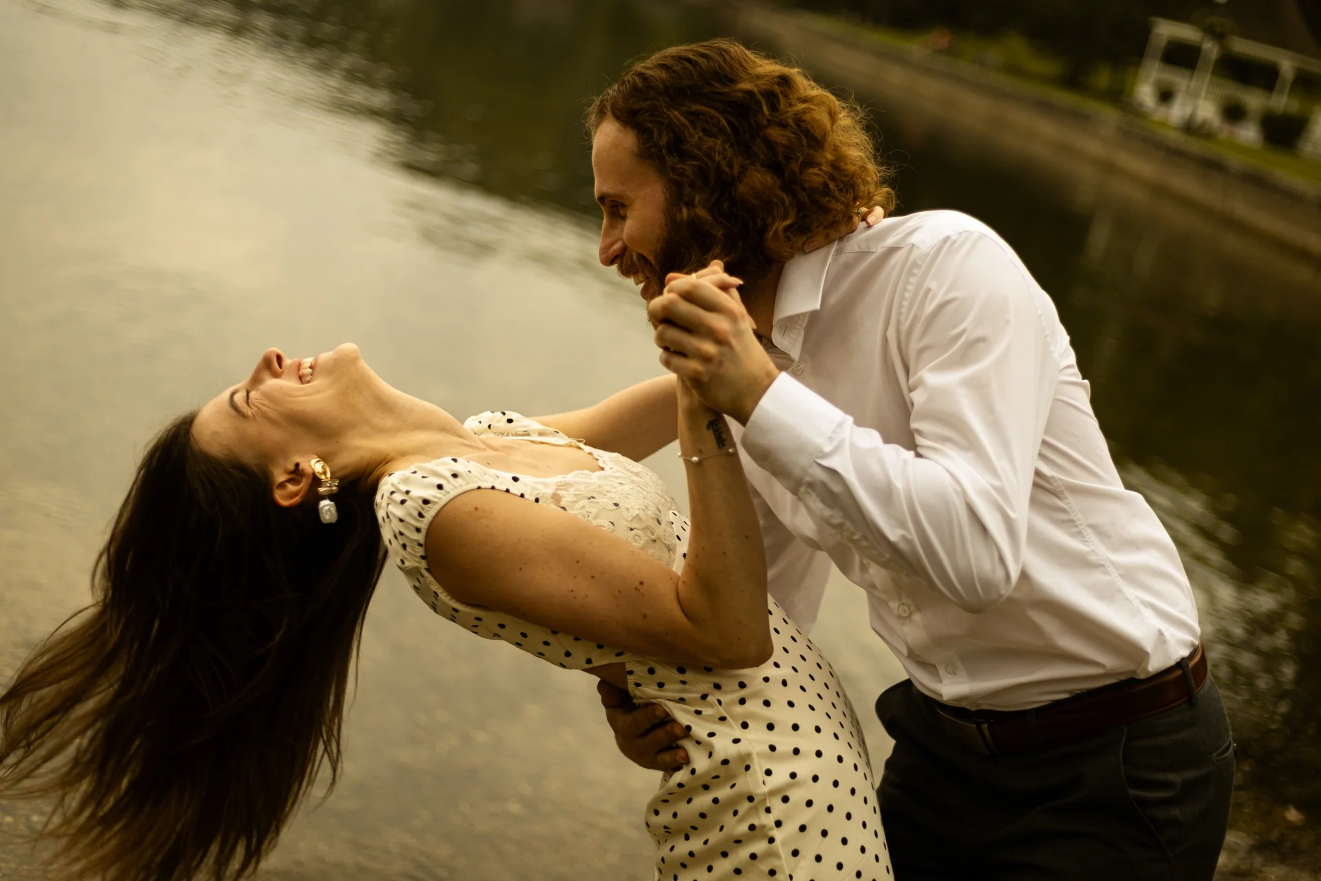 Un couple rit et danse sur une plage dans une lumière dorée.