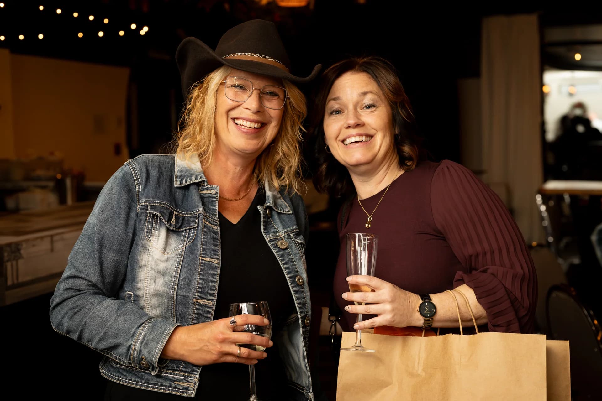Two people smile with drinks in hand at an evening event.
